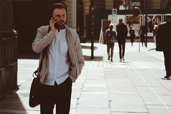 Homme avec un sac debout dans la rue parlant au téléphone