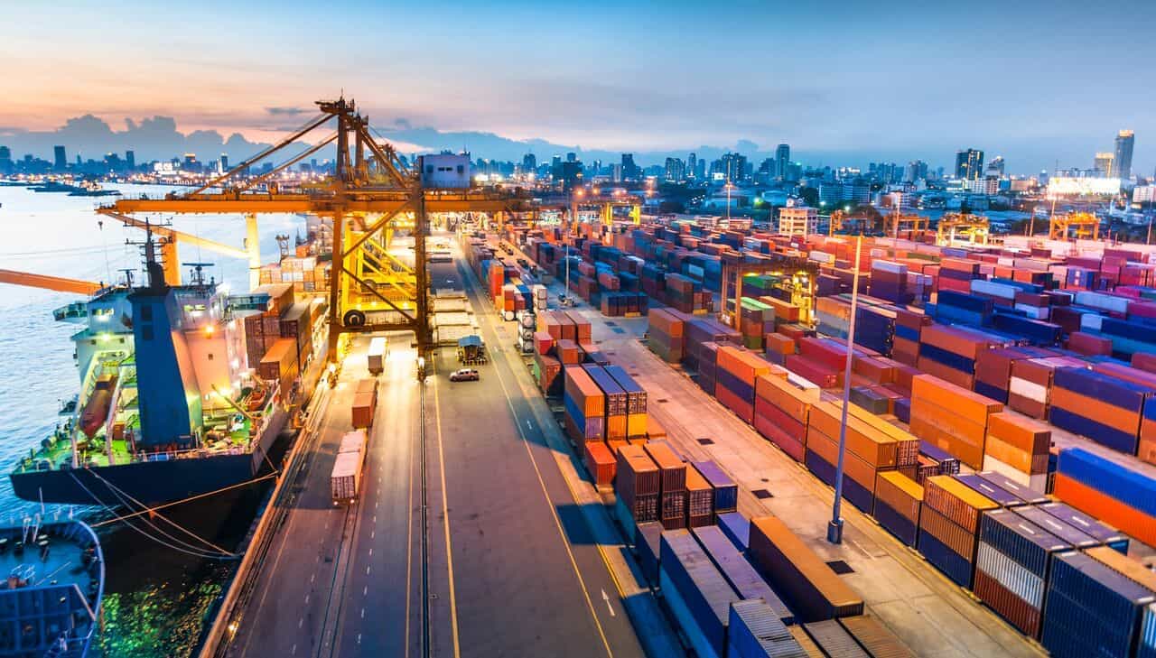 aerial view of a commercial port with cranes loading shipping containers onto freight vessels