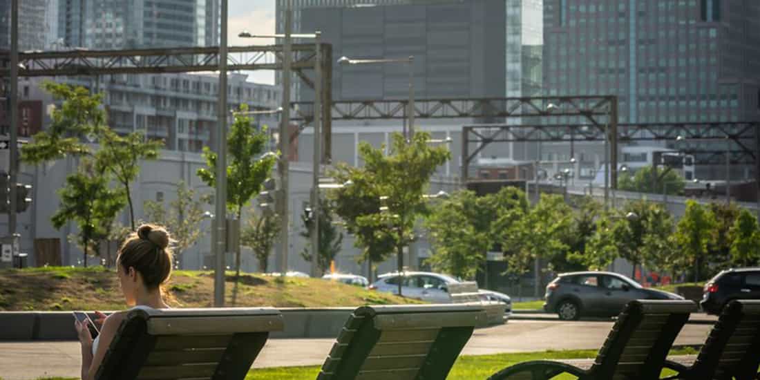 a real estate broker sits on a bench reviewing office properties on their phone