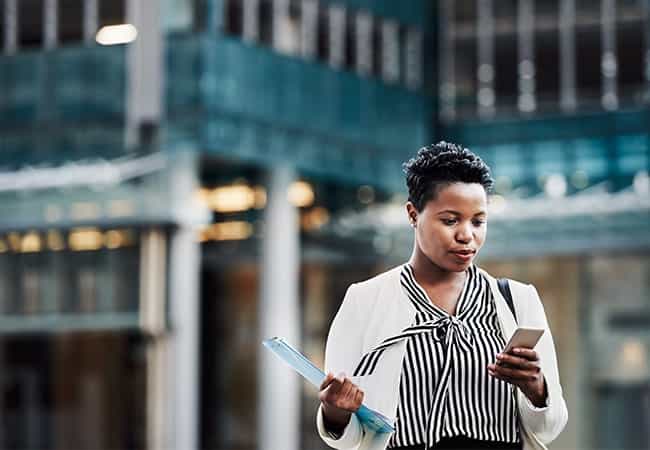 investor reviews commercial office buildings for sale on a mobile device in front of a property
