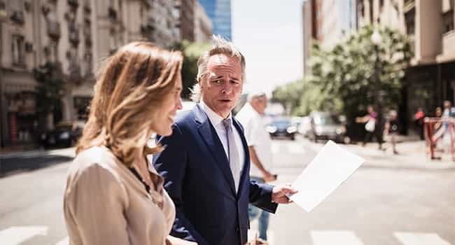 real estate agent discusses lease proposal with executive of a non-profit while crossing the street in a business district
