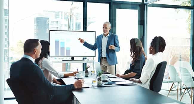 commercial real estate advisor presents statistics to real estate team in a glass enclosed meeting space