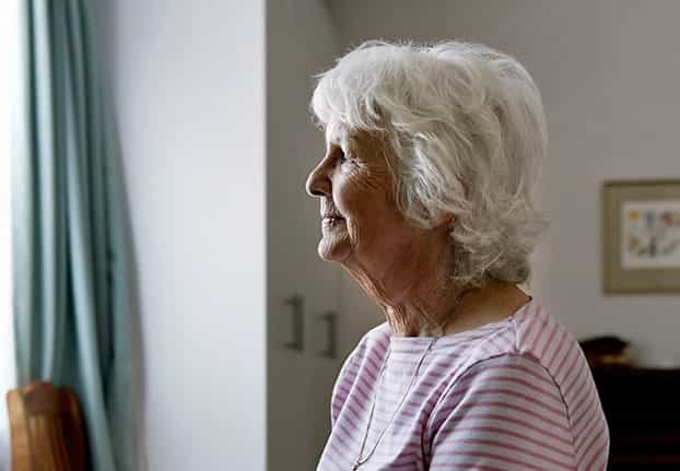 Senior regarde par une fenêtre