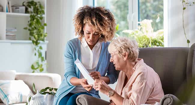 a senior housing professional discusses a document with an elderly resident