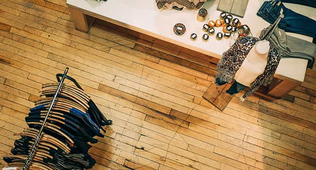 Vue aérienne d'un espace de vente au détail avec des planchers en bois, un porte-vêtements, un mannequin et des produits sur la table