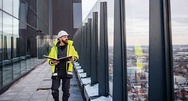 a facility manager walks on the roof of a commercial property while looking towards the horizon
