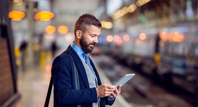 an automotive property owner reviews a real estate proposal on a tablet while waiting on a subway platform