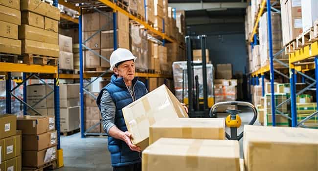 a logistics worker loads boxes onto a pallet in an industrial warehouse