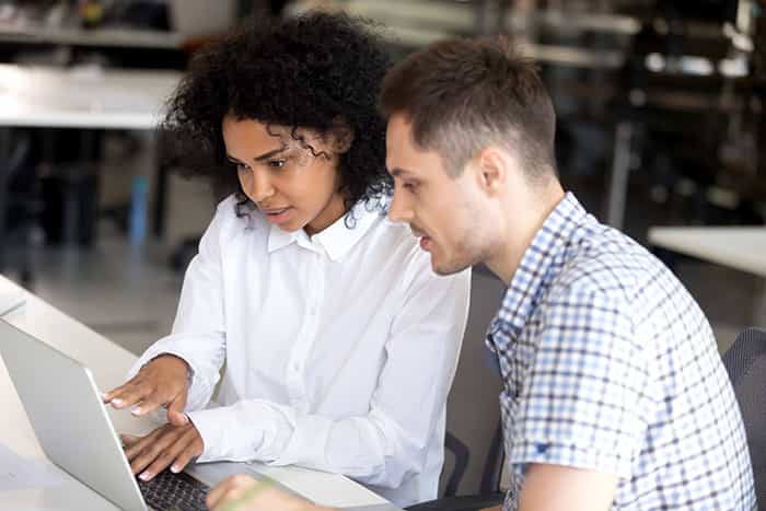 An image of two young professionals collaborating around a laptop