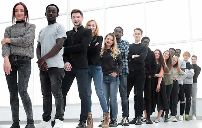 An image of a group of young professionals stood in a line, smiling at the camera