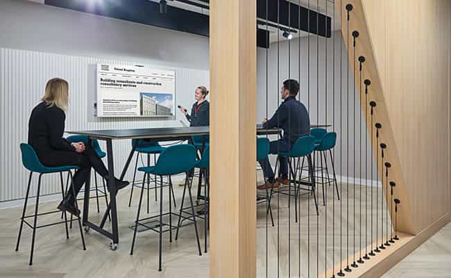 An image of a group of young professionals sat around a desk looking at a large monitor