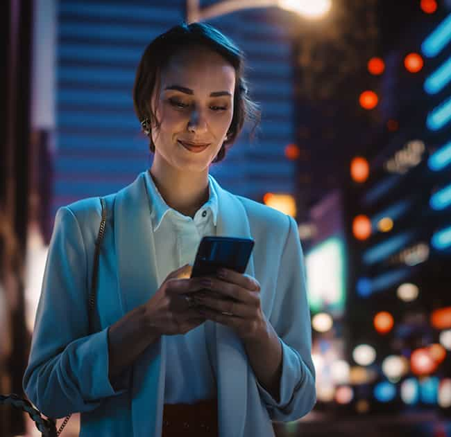 A lady looking at a smartphone in a busy city