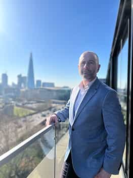 Paul Broad stood on a balcony with the London skyline in the background