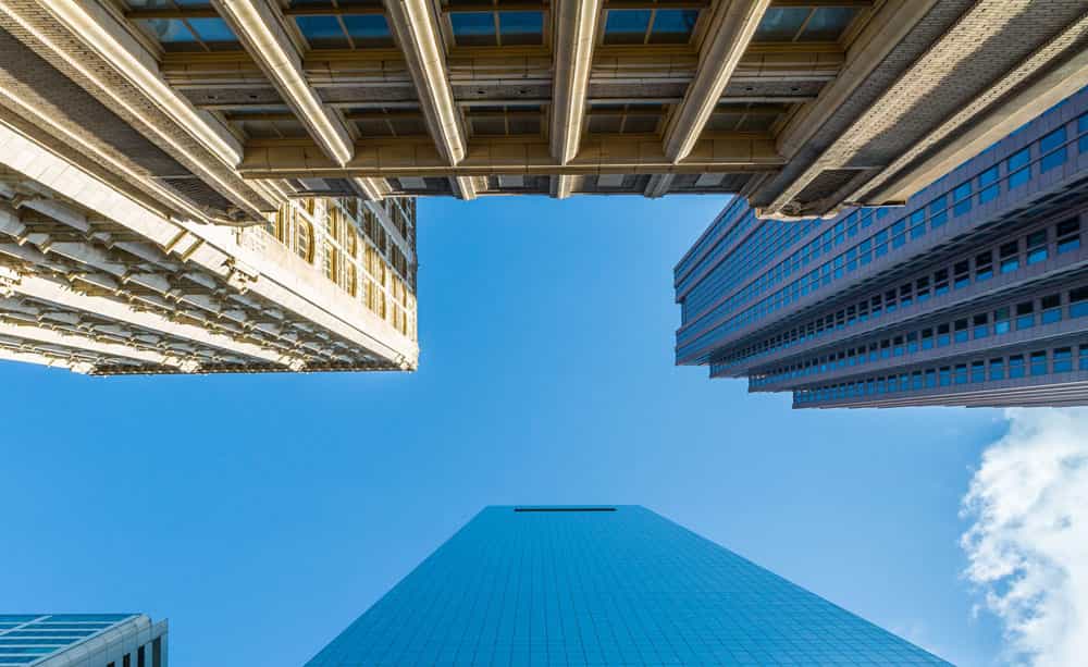 An external shot of high rise office buildings taken from street level, and looking up towards the sky