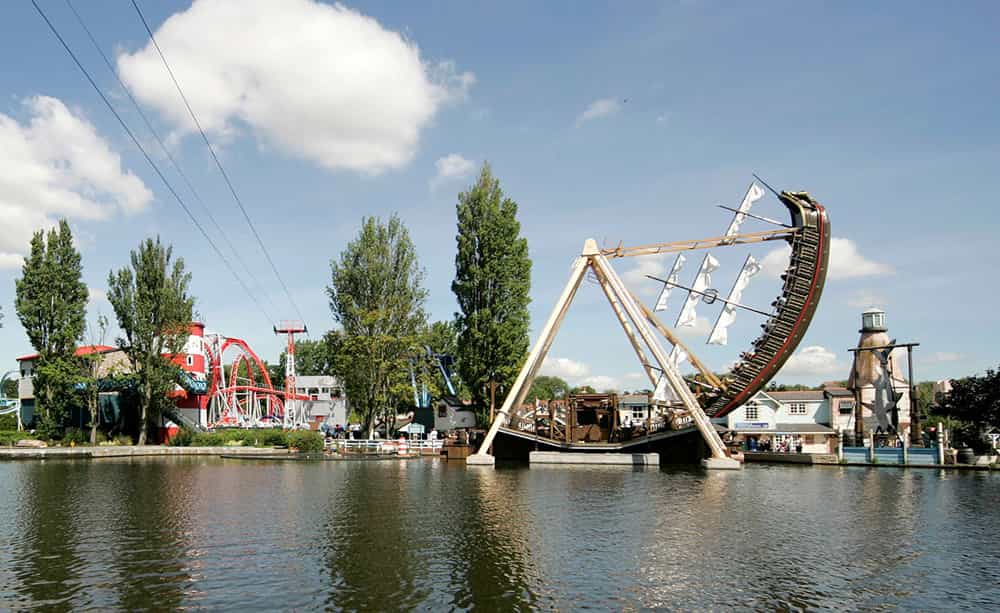 An image of a group of fairground rides taken across the water from the banks of a lake