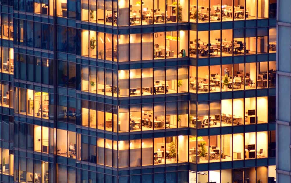 An external building of a high rise office block with lights on taken at night