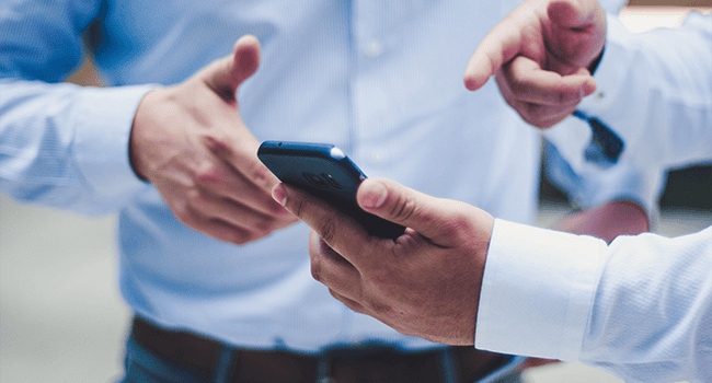 An abstract image of two people looking and pointing at a mobile phone
