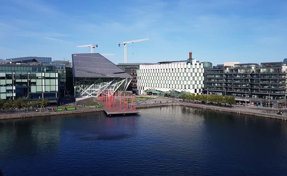 An image of a modern office building with a river in the foreground of the picture