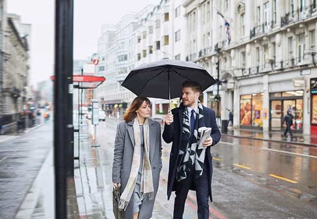 Moncton retail broker walks with client under umbrella on a rainy street discussing investment opportunities